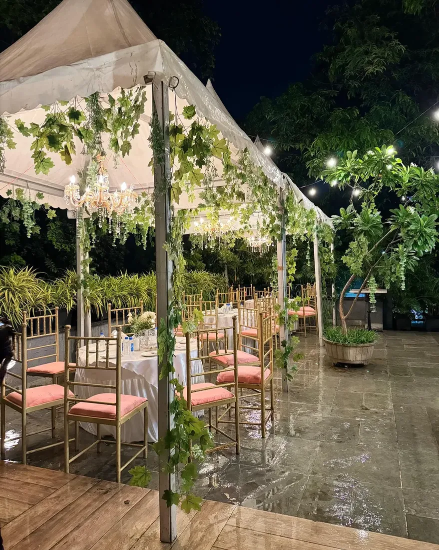 Garden dinner setup with chandeliers and greenery