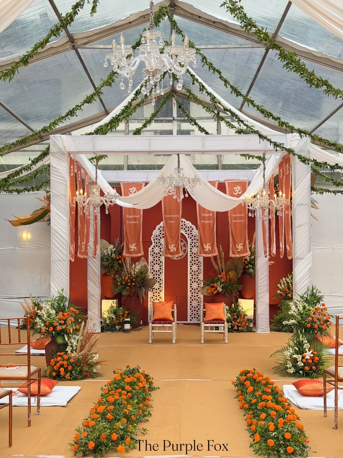 White-draped mandap with crystal chandeliers and marigold florals
