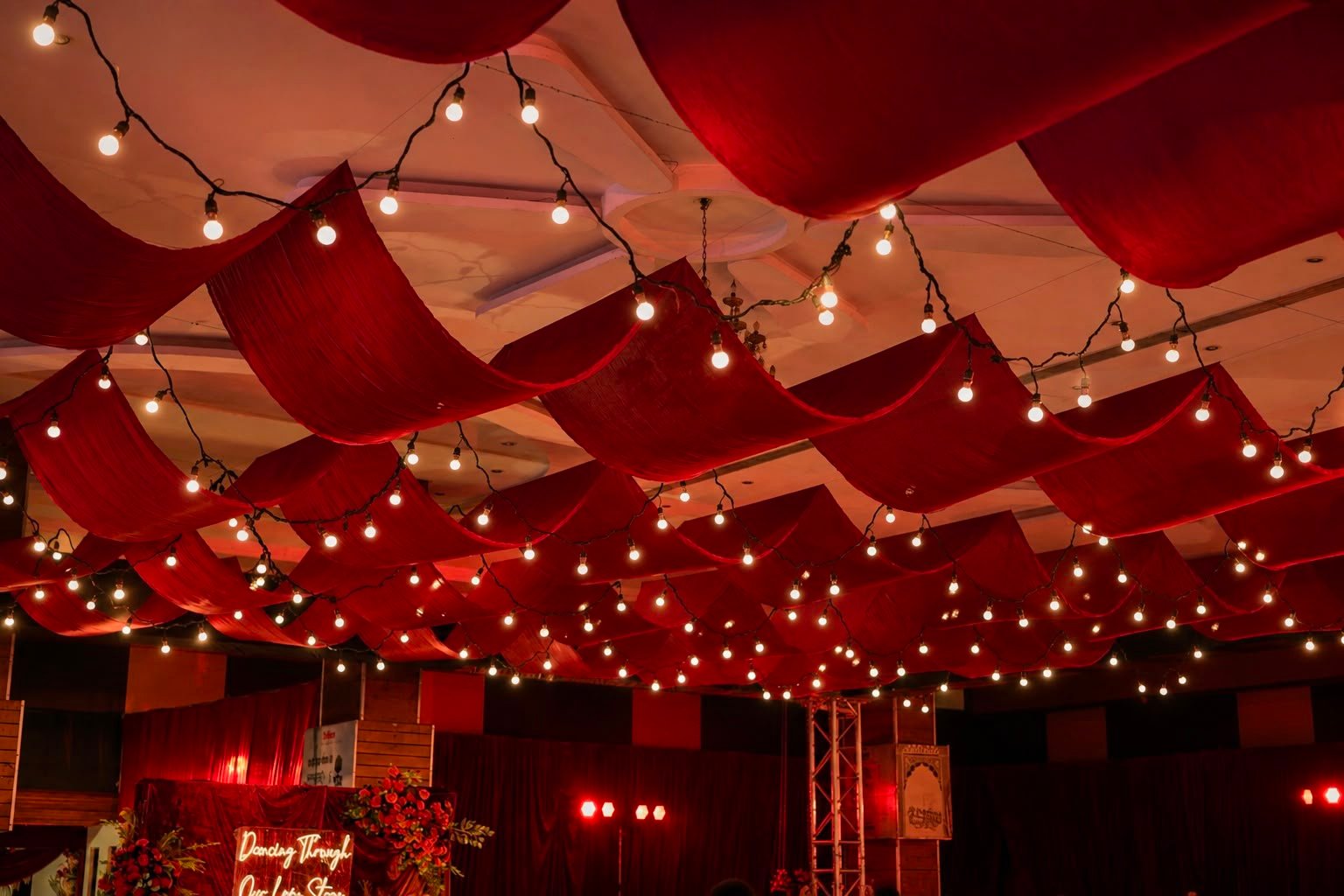 Draped red fabric ceiling with fairy lights over a reception